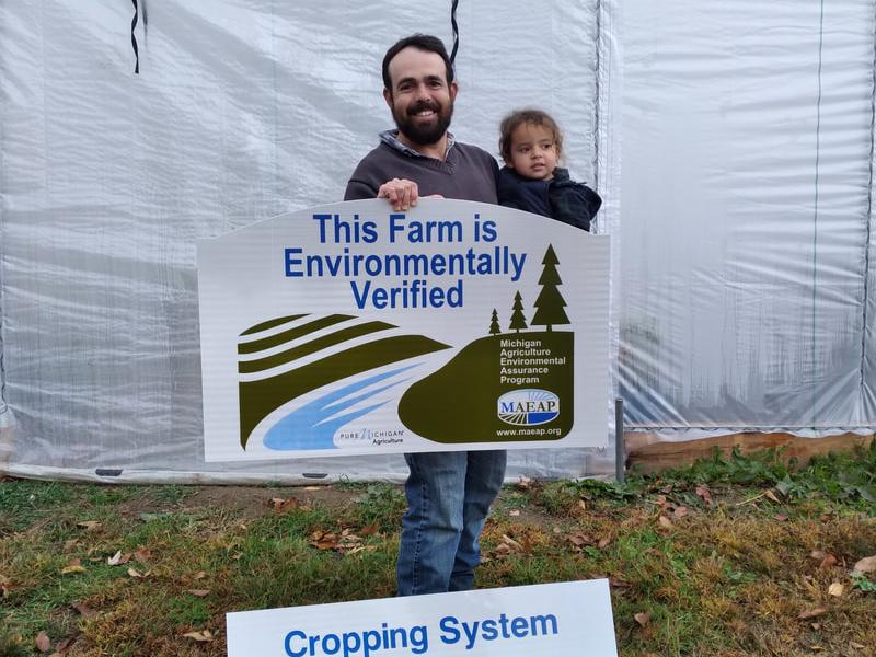 MAEAP - Father and child with "This Farm is Environmentally Verified - Cropping System" sign in front of greenhouse