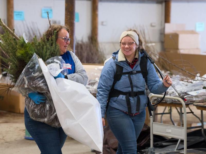 Volunteer and staff with tree orders and watering pack (Photo Credit: Paul Michael Peters)