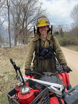 Plantwise staff managing a prescribed burn with torches and quad vehicles.