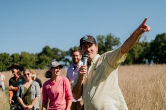 Shannon Brines holding a microphone, pointing at trees