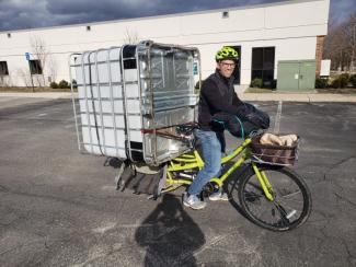 Bicycle rider with a 275 gallon tote balanced on the bike rack!